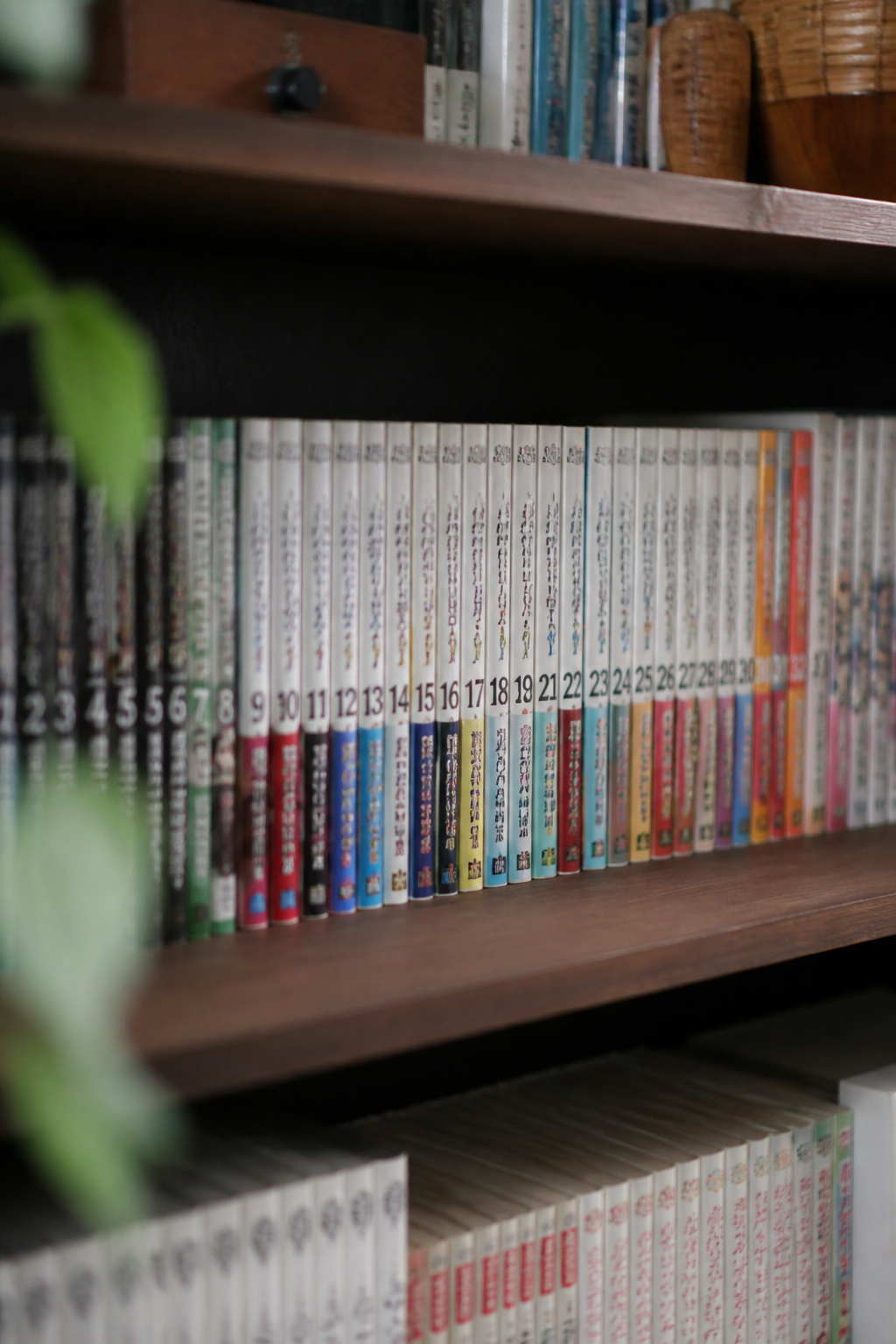 漫画の単行本が巻数順に並んだ棚。新書判とB6判が混在し、背表紙の番号が一列に続いている